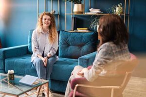 woman on blue couch talks with therapist in a psychotherapy program