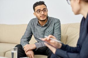 man wearing glasses talks with therapist about starting a tms therapy program 