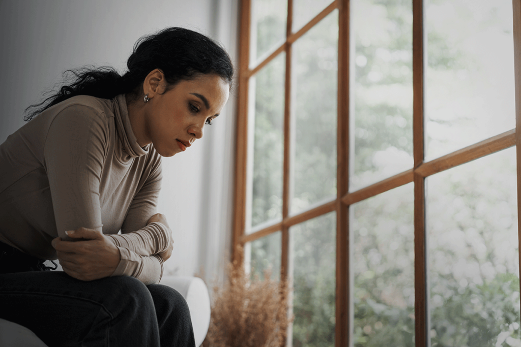 a person looks sad near a gray window wondering how to treat seasonal affective disorder